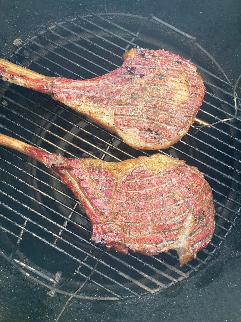 this shows two large steaks on a grill with a meat thermometer to cook to the right temperature