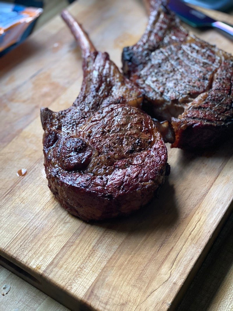 this hows a picture of two big steaks resting on a cutting board after being taken off the grill