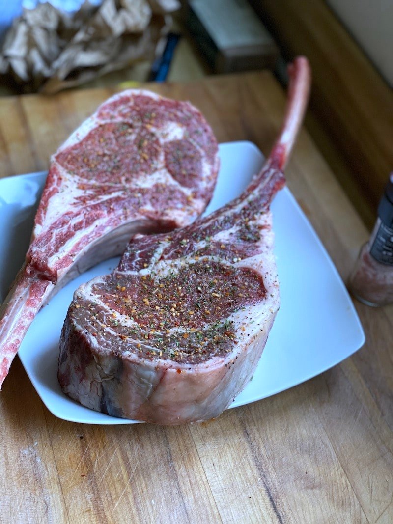 this is a picture of two tomahawk steaks seasoned right before grilling