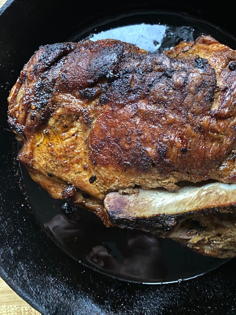 pork shoulder in a cast iron skillet after it's cooked four hours