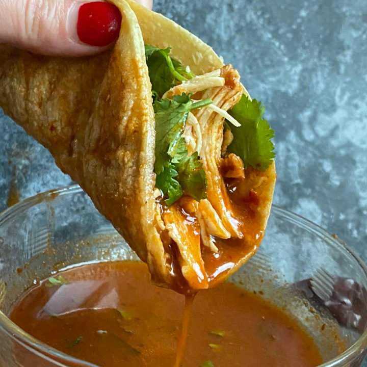 this is a photo of a chicken birria taco being dipped into consomme