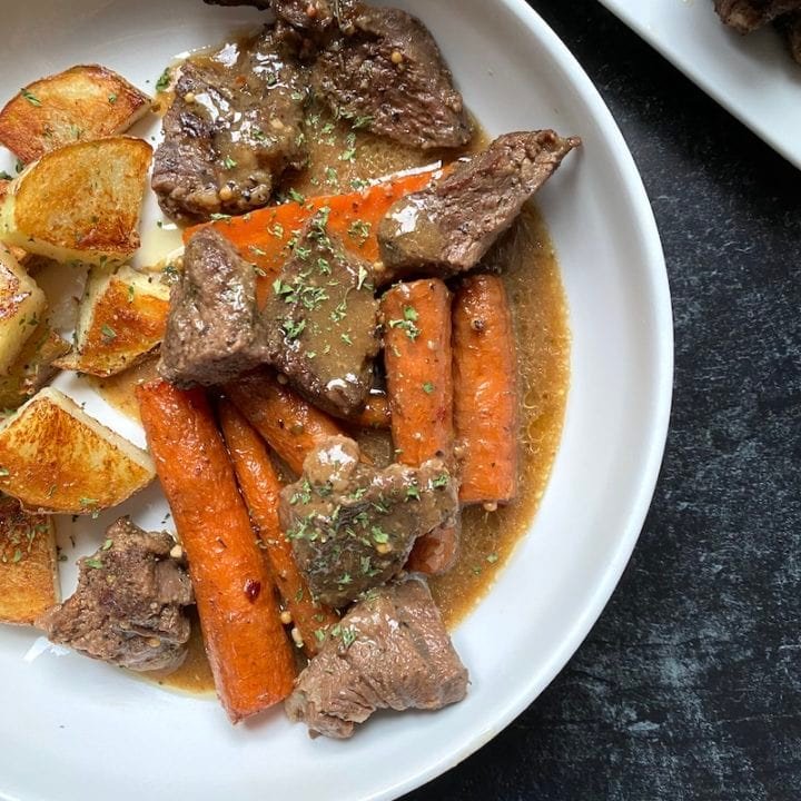 this is a photo of braised beef with carrots and gravy