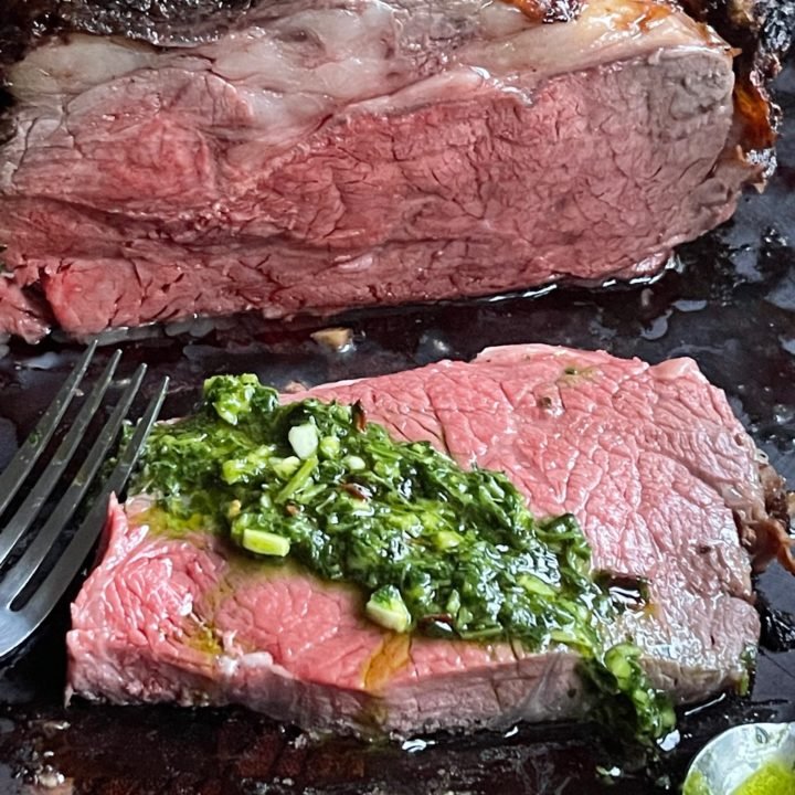 This is a photo of sliced oven roasted standing rib roast with chimichurri sauce