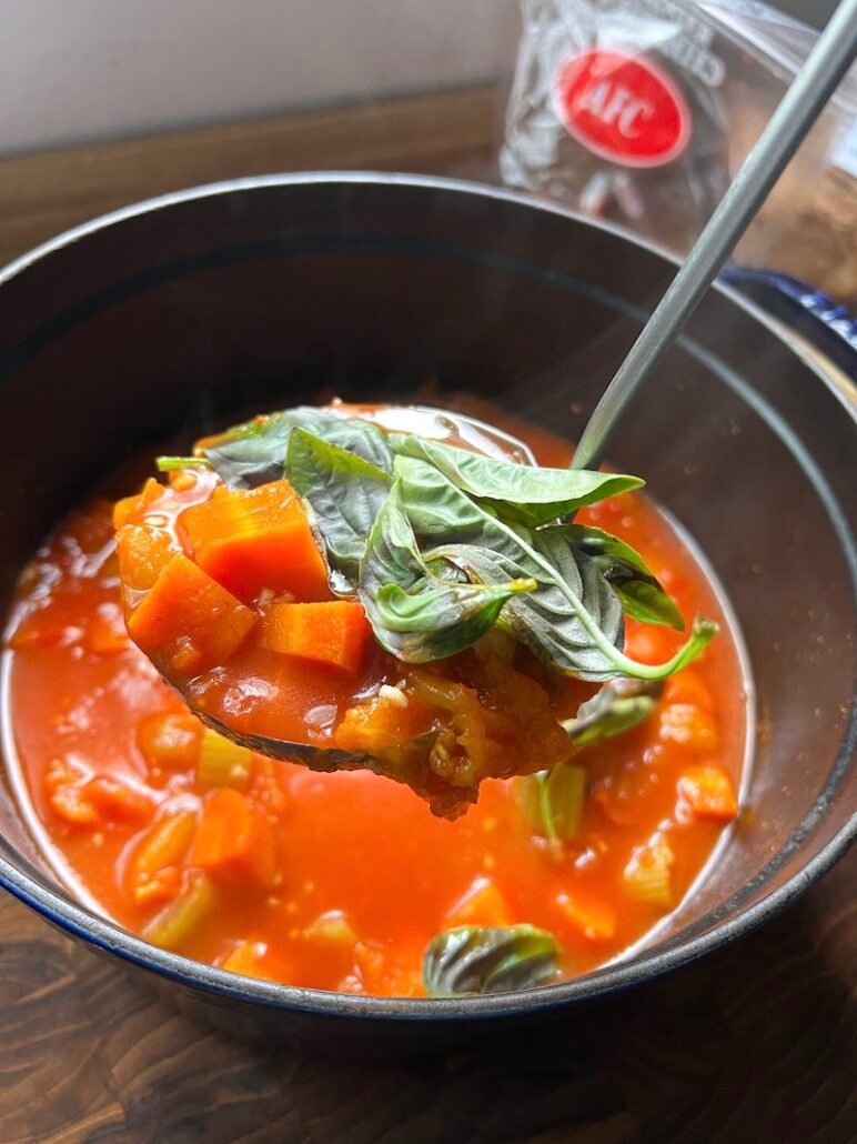 this is a ladle of tomato soup that is going to be blended