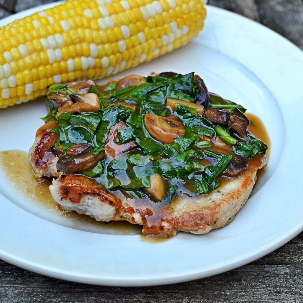 this is a plate of pork chops with spinach mushroom sauce