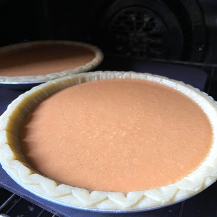 this is a photo of pumpkin pie going into the oven to cook