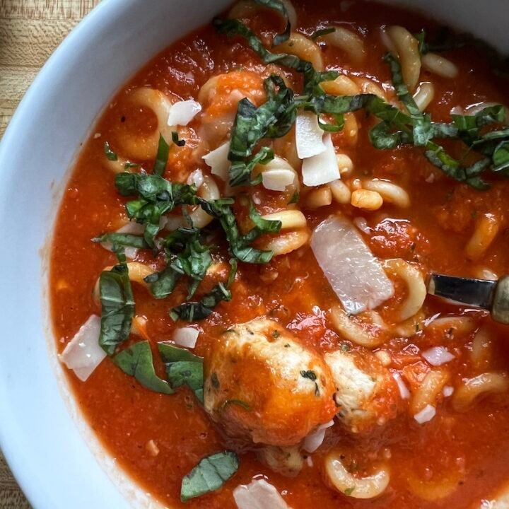 This is a bowl of tomato soup with Italian meatballs.