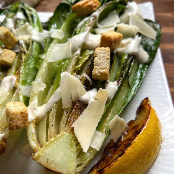 this is a plate with charred romaine caesar salad