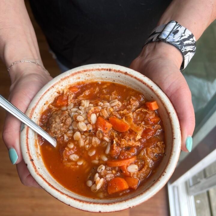 this is a bowl of barley meatball soup with vegetables