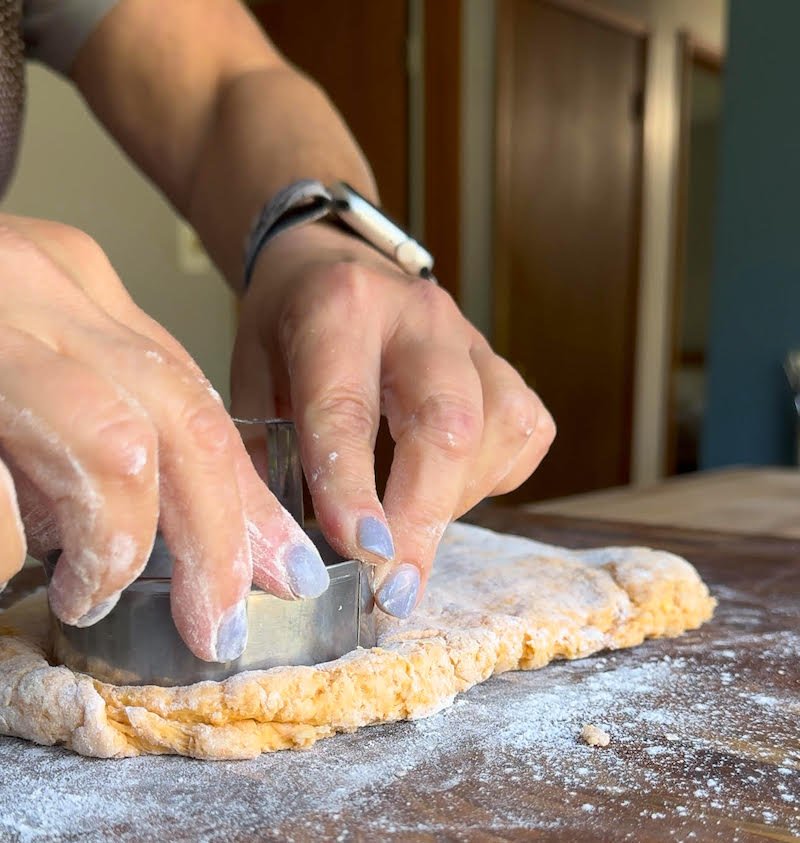 using a biscuit cutter to cut biscuits